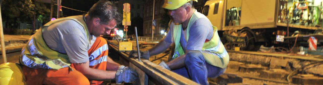 Arbeiter mit Maschinen verlegen in der Nacht neue Gleise