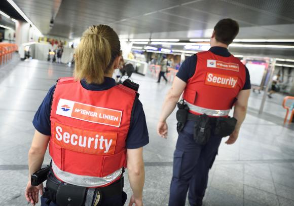 zwei Mitarbeiter des Sicherheitsdienstes in roten Warnwesten in der U-Bahn