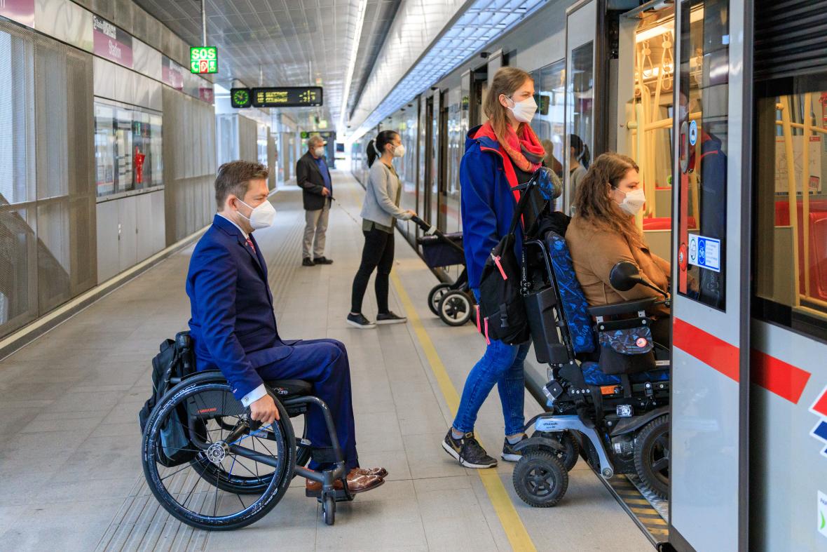 zwei Rollstuhlnutzer fahren in die U-Bahn die Klapprampe überbrückt den Spalt zwischen Fahrzeug und Bahnsteig