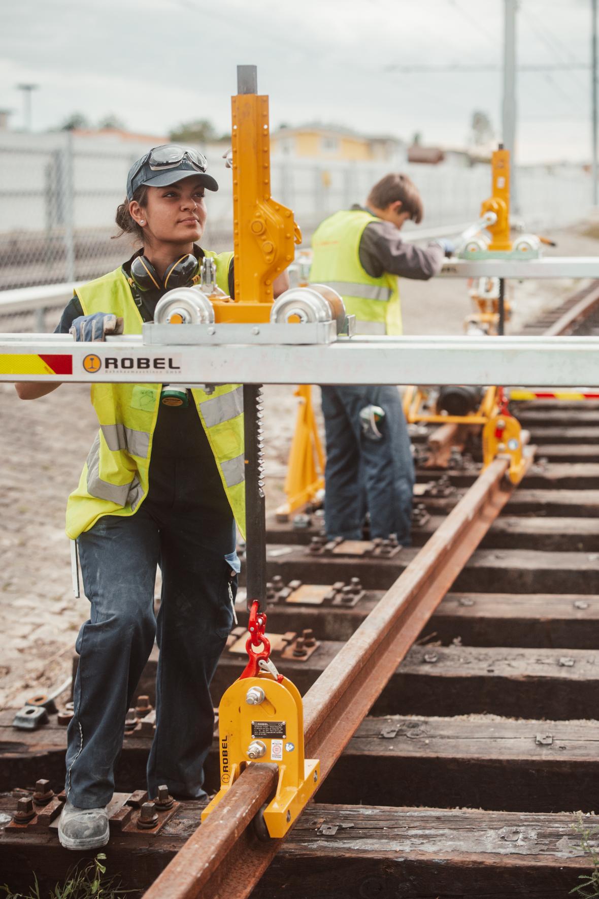 a young woman and a young man working on rail tracks