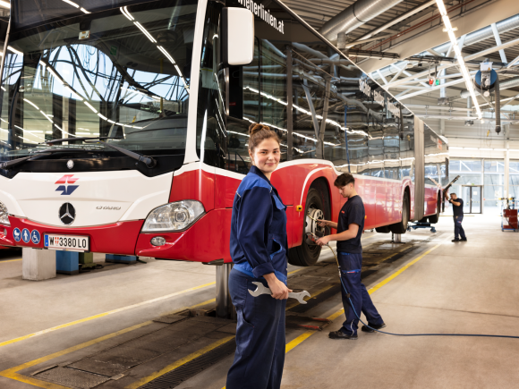Frau und Mann in Wiener Linien Arbeitskleidung arbeiten in einer Werkstatt an einem Linienbus