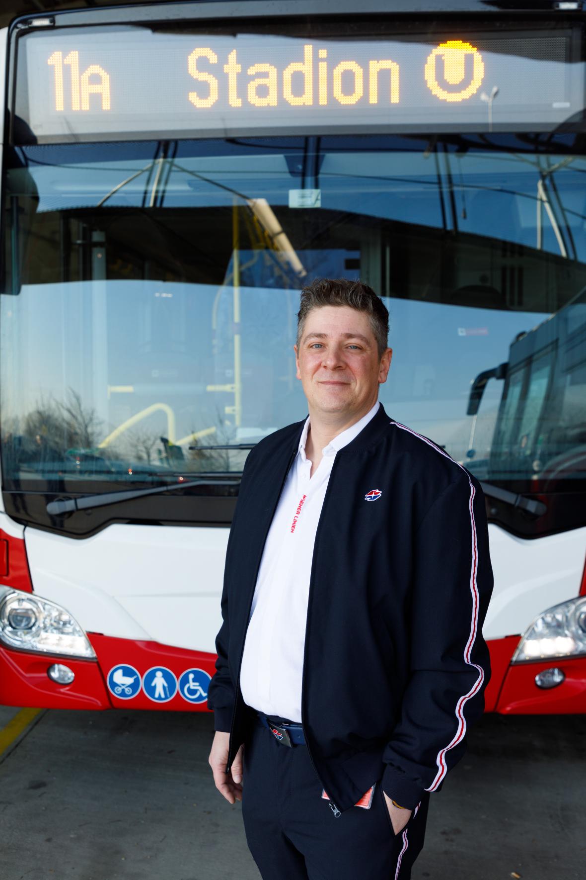 a bus driver in Wiener Linien work clothes standing in front of a public bus
