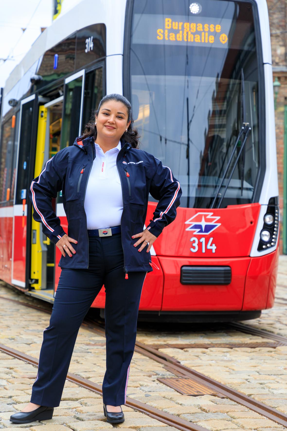 a female tram driver standing in front of a flexity tram