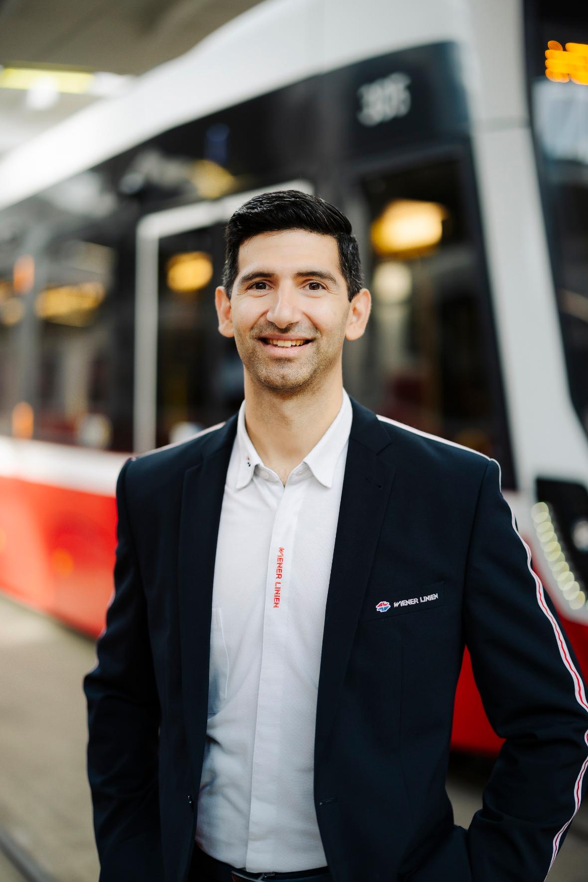 ein Mann in Wiener Linien Uniform steht vor einer Straßenbahn