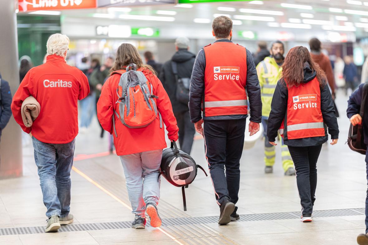 vier Personen mit roten Warnwesten sind im U-Bahn-Bereich unterwegs
