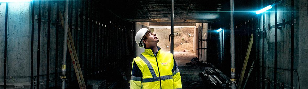 a man wearing a helmet on a construction site is looking up towards the light