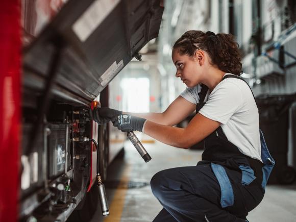 a young woman in Wiener Linien work clothes performing maintenance work on a public bus