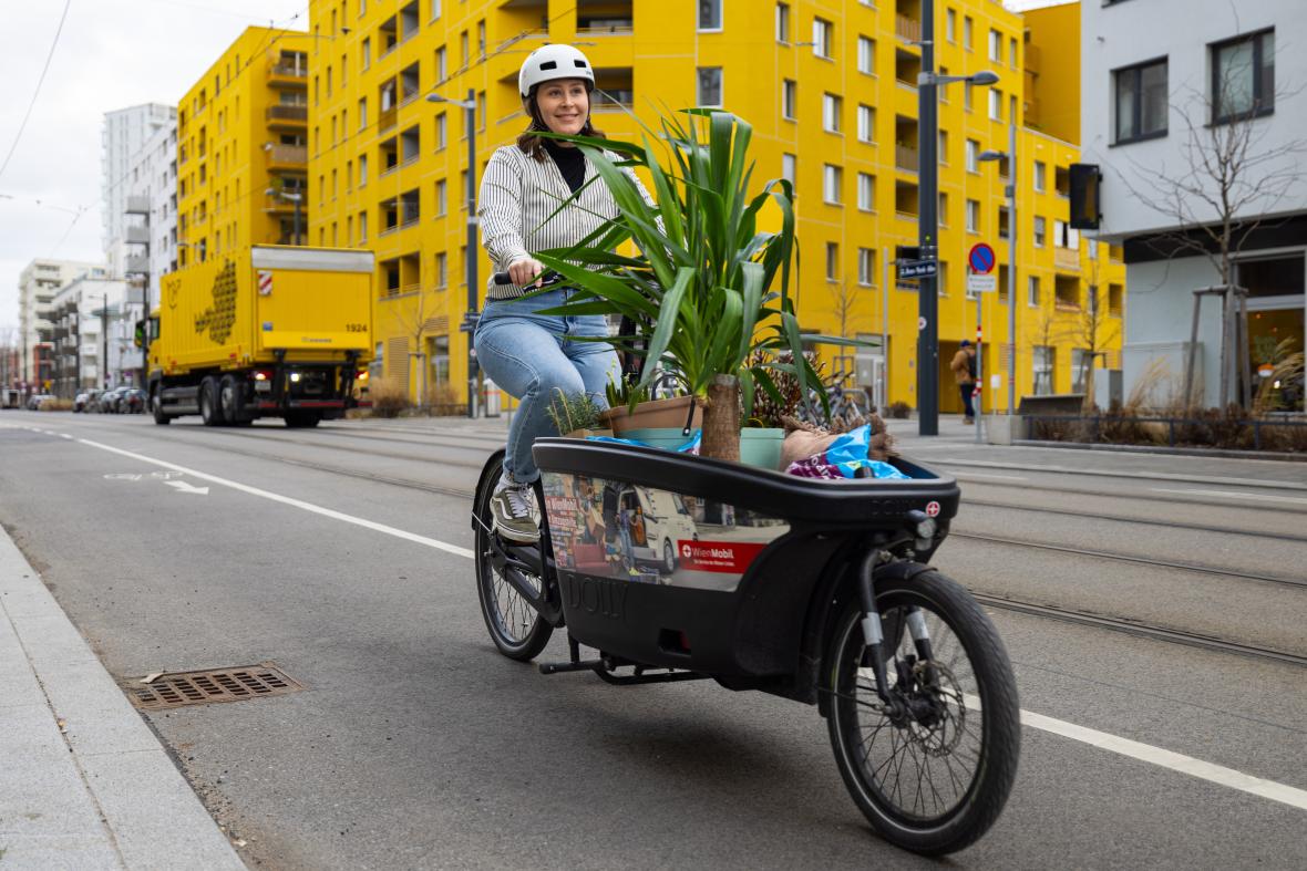 junge Frau fährt mit vollgepackten WienMobil Lastenrad durch das Nordbahnviertel in Wien