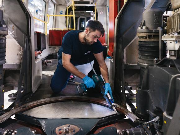 Mann in Wiener Linien Arbeitskleidung arbeitet in einer Werkstatt im Inneren eines Schienenfahrzeugs