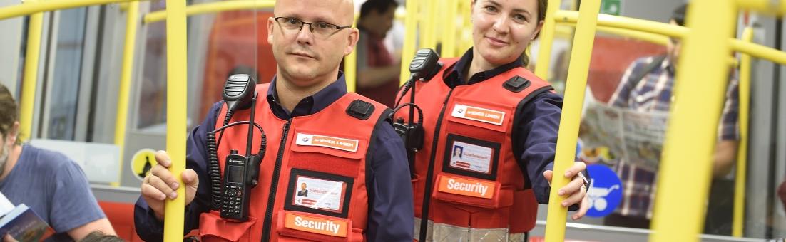 zwei Wiener Linien Mitarbeiter mit roten Sicherheitswesten stehen in einem U-Bahn-Zug und lächeln in die Kamera