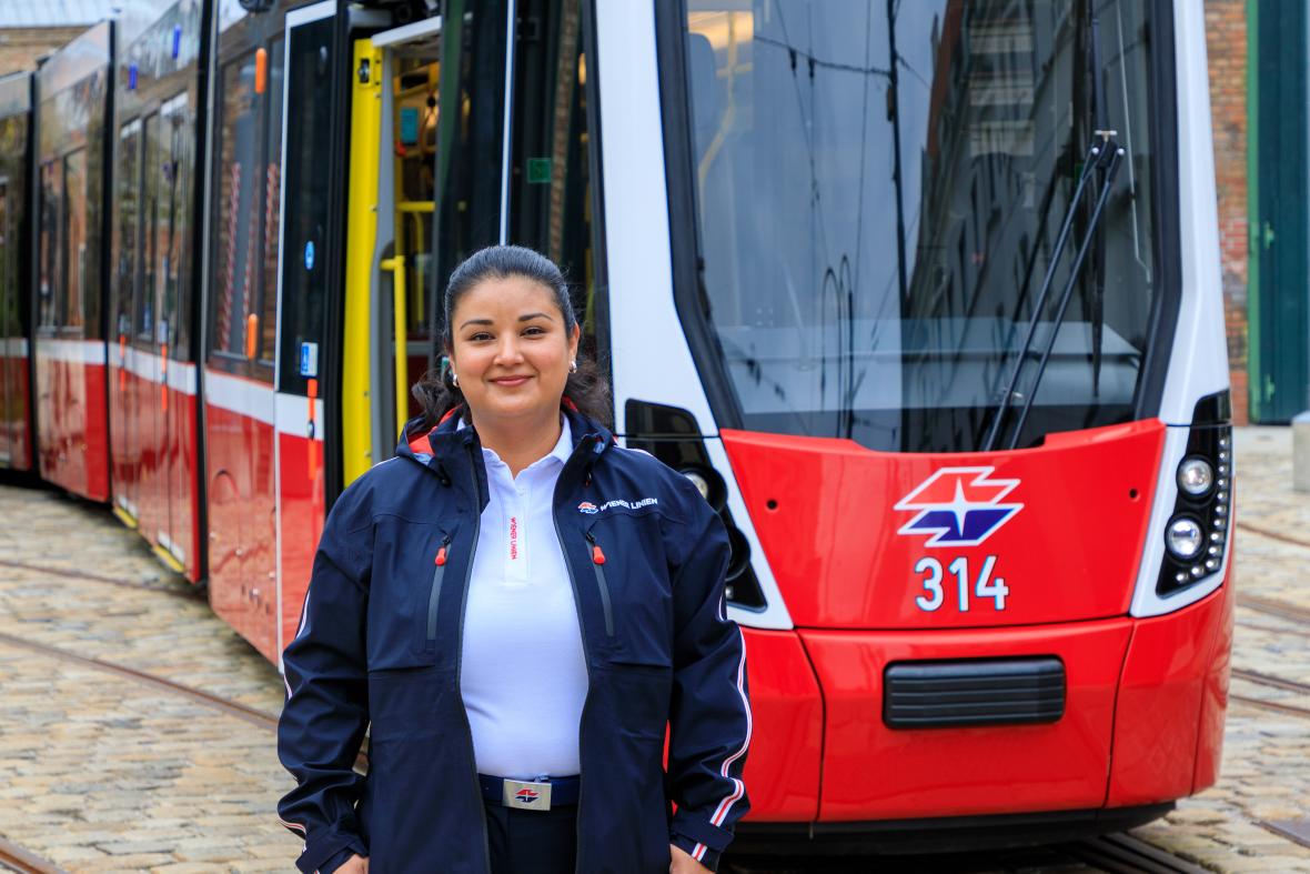 Frau in blauer Uniform vor einer roten Straßenbahn